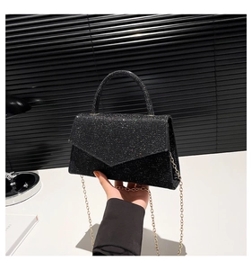 Detail of black sequin envelope handbag with round handle and gold chain strap