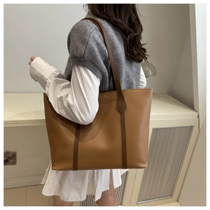 Detail of tan faux leather tote bag with contrasting coffee brown straps on model