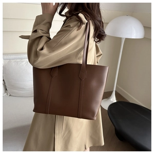 Deep brown leather tote bag worn by model showing large capacity and minimalist style