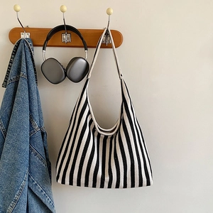 Détail d'un sac cabas en toile à rayures noires et blanches suspendu avec une veste