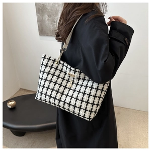 Détail du sac cabas à carreaux avec chaîne dorée et breloque cerf sur un mannequin