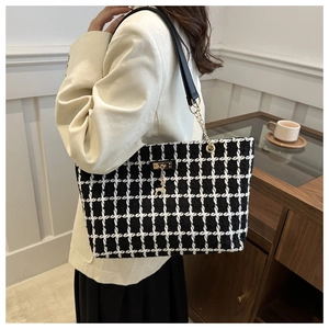 Détail d'un sac cabas en tweed à carreaux noir et blanc avec chaîne dorée sur l'épaule