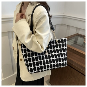 Détail du sac cabas à carreaux avec pendentif cerf doré et bandoulière en cuir noir