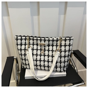 Détail du sac cabas en tweed noir et blanc avec chaîne dorée et breloque cerf