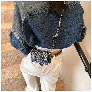 Detail of mini leopard print crossbody bag with acrylic chain strap on casual denim look