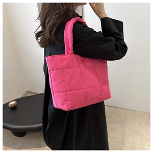 Gros plan du sac cabas matelassé rose vif montrant le tissu doux style doudoune