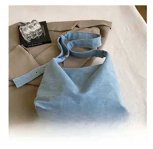 Détail du sac hobo en jean bleu clair avec bandoulière à œillets sur mise en scène