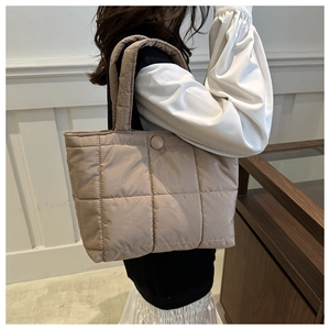 Gros plan du sac fourre-tout matelassé beige avec motif à carreaux élégant et bouton assorti