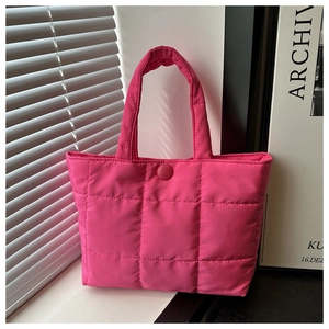 Close-up of bright pink quilted tote bag with padded squares and round button closure