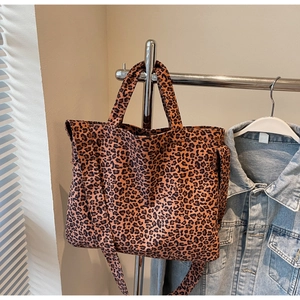 Detail view of large leopard print tote bag hanging with adjustable shoulder strap