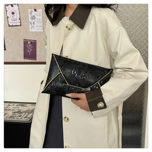 Close-up of black snakeskin patterned envelope clutch bag with gold metallic trim