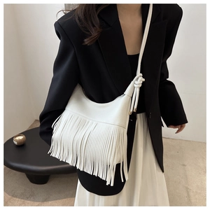 Detalle del bolso de hombro blanco en forma de luna con flecos y textura de grano de lichi