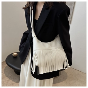 Detail of creamy white fringe tassel shoulder bag in pebble grain PU leather on model