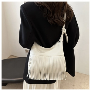 Bolso tote de cuero blanco con flecos y correa de hombro anudada usado por modelo