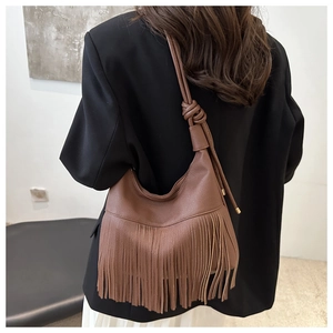 Close-up of brown leather tote featuring stylish fringe details and twisted rope strap