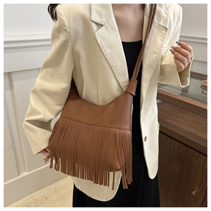 Detailed close-up of a caramel leather crossbody bag featuring long bohemian style fringes