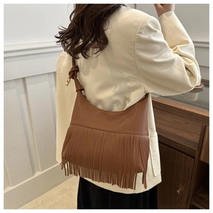 Close-up of brown lychee grain leather tote bag featuring long fringe and knotted shoulder strap