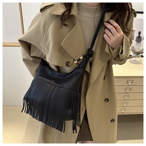 Detalle de bolso bandolera de cuero granulado negro con elegantes flecos y borlas