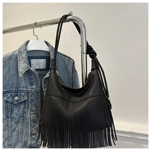 Detalle de bolso hobo negro con flecos, textura de lichi y herrajes dorados lujo
