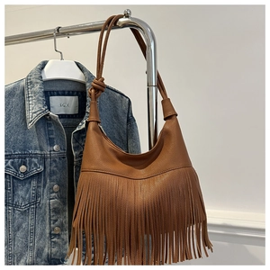 Detalle de bolso hobo de cuero marrón con patrón de lichi, flecos largos y correa anudada