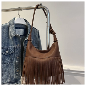 Detalle del bolso hobo de cuero marrón con flecos largos y un asa con nudo