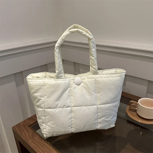 Sac fourre-tout matelassé minimaliste en nylon crème sur une table en bois foncé