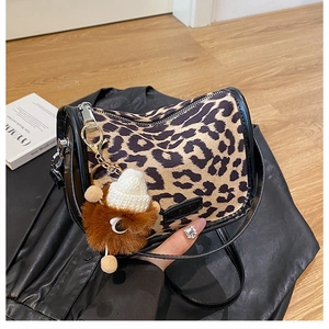 Dettaglio borsa a cilindro leopardata con ciondolo a pompon e finiture in pelle nera
