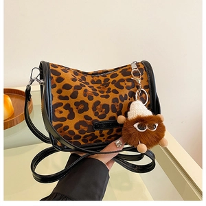 Dettaglio borsa a tracolla leopardata con bordo in pelle nera e ciondolo di peluche