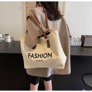Detail showing high-capacity canvas tote bag with brown straps and Paris print worn by model