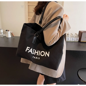 Detail of black canvas tote bag with Fashion Paris lettering and leather handles