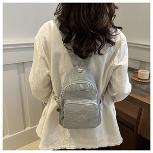 Lifestyle view of a mini silver quilted backpack with pleated texture and metal zippers