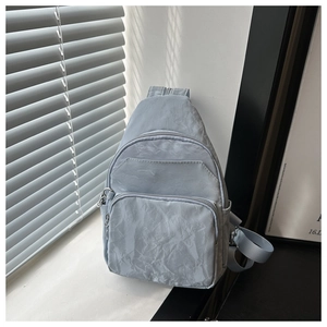 Detailed view of light blue-grey pleated nylon crossbody bag with multiple zip pockets