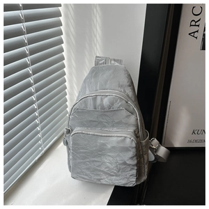 Detail of grey wrinkled nylon chest bag featuring layered front zip pockets and side buckle