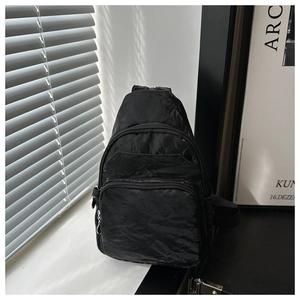 Close-up of black pleated nylon chest bag with multiple zippers and vintage texture