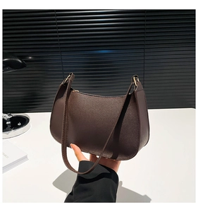 Detailed close-up of dark brown Saffiano leather texture and gold hardware on baguette bag