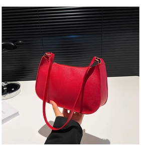Close-up of red crossbody bag with cross-grain leather texture and zipper detail