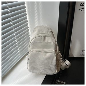 Detail view of beige nylon crossbody chest bag showing zippers and textured fabric