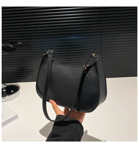 Close-up of black cross-grain leather texture and gold hardware on hobo shoulder bag