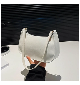 Detailed shot of white litchi grain leather shoulder bag with gold metal hardware