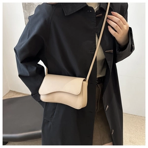 Detailed view of cream-beige crossbody bag with unique wavy flap and leather texture