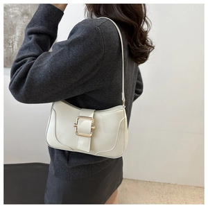 Detail of a creamy white underarm bag with a large golden square buckle and glossy finish