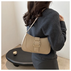Side view of beige underarm bag with gold metal buckle showing fit and texture