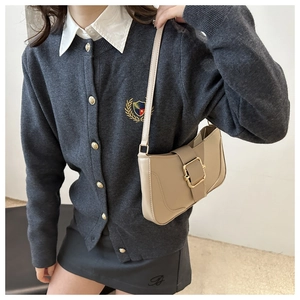 Detail of beige baguette shoulder bag with gold square buckle and smooth leather texture