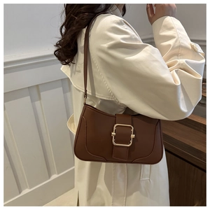 Detail of a vintage dark brown leather underarm bag with a golden metal buckle for women