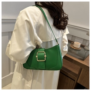 Detailed view of green leather underarm bag with gold buckle on shoulder