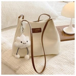 Detail of cream waffle texture tote bag with brown leather straps and cloud charm