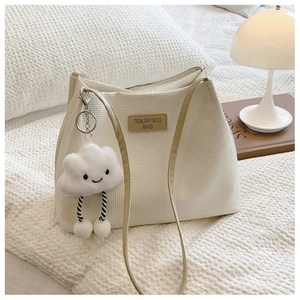 Close-up of white waffle texture tote bag with a cute cloud plush charm on a bed
