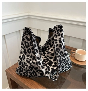 Detail of leopard print tote bag with wide shoulder strap on a wooden table