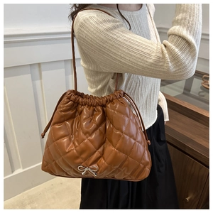 Brown quilted bucket bag with drawstring and silver bow buckle shown on a model