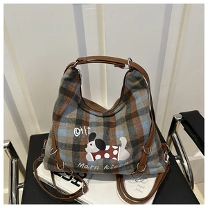 Detail of plaid wool tote bag with cartoon dog print and brown leather handles